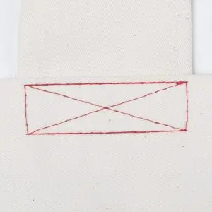 Czerwony szew krzyżowy na białym materiale, detal wykończenia