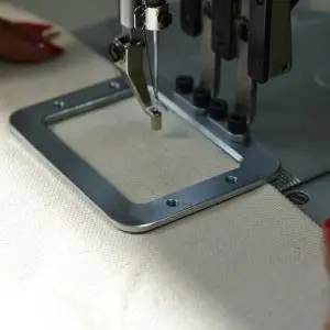 Igła maszyny do szycia na szarym materiale, detal szycia